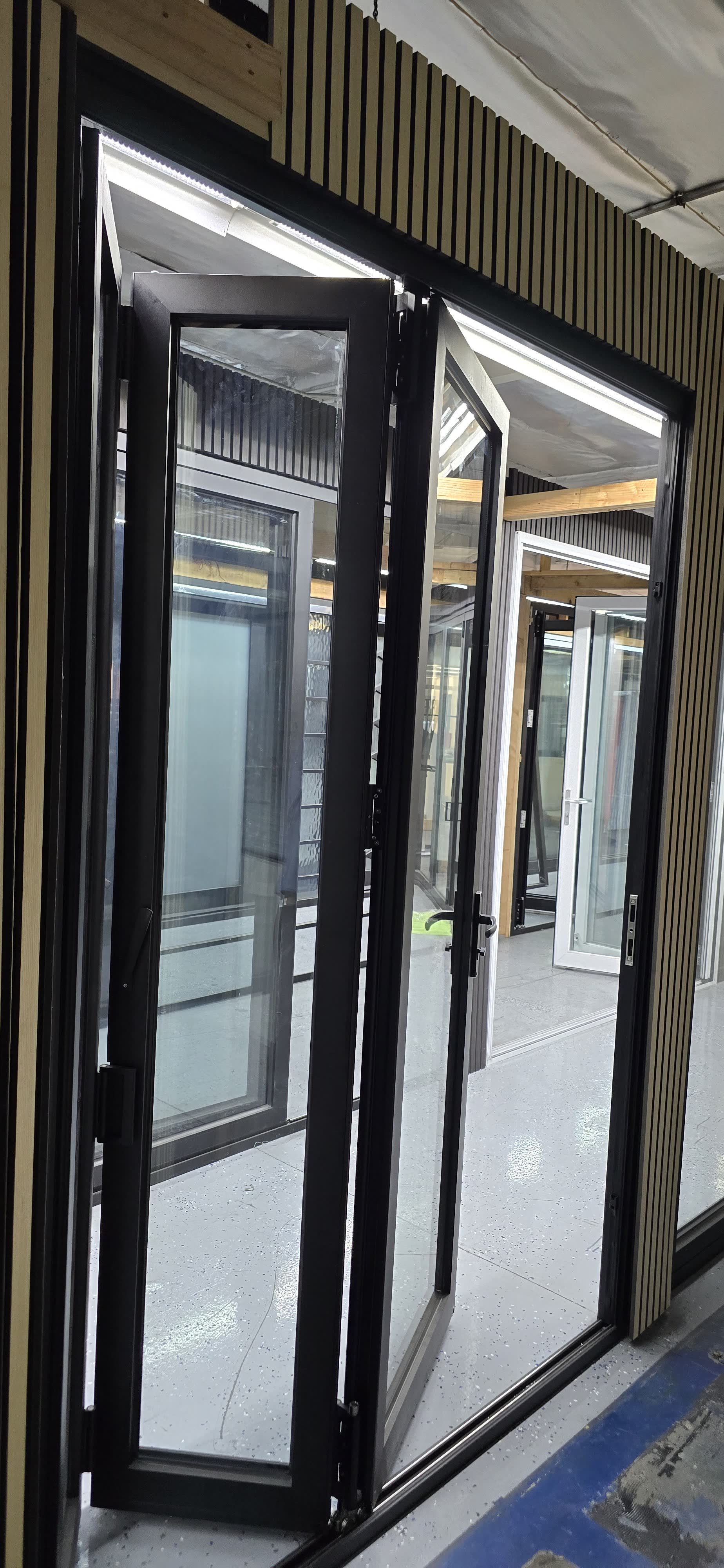 Aluminum bi-fold doors with slim black frames open in the showroom