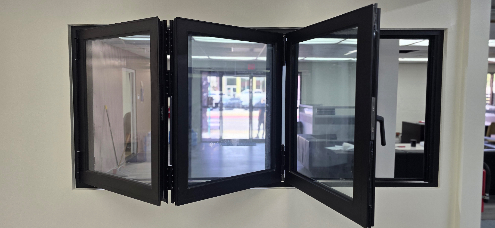 Black aluminum bi-fold window folded open in a wall opening